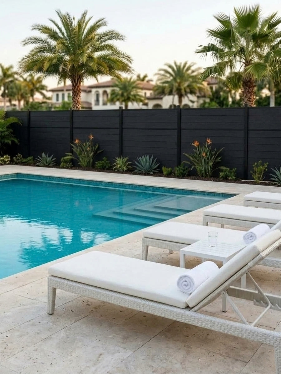 Black Center Trim composite fence enclosing a pool area with palm trees and white loungers