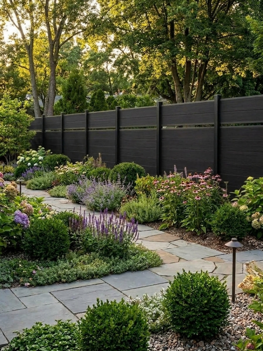 Black single divider composite fence bordering a lush flower garden and stone path