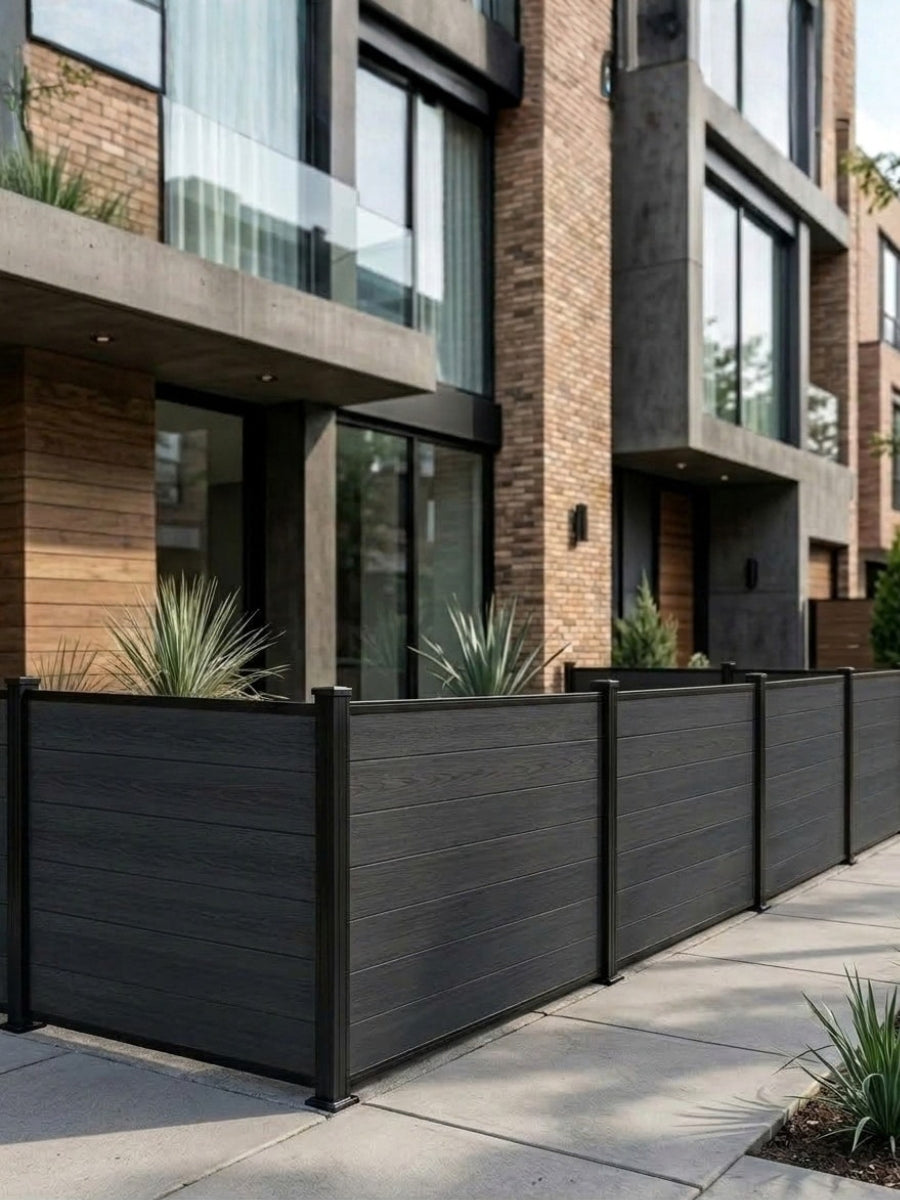 Black composite privacy fence panels enclosing a sidewalk patio outside a modern brick residence