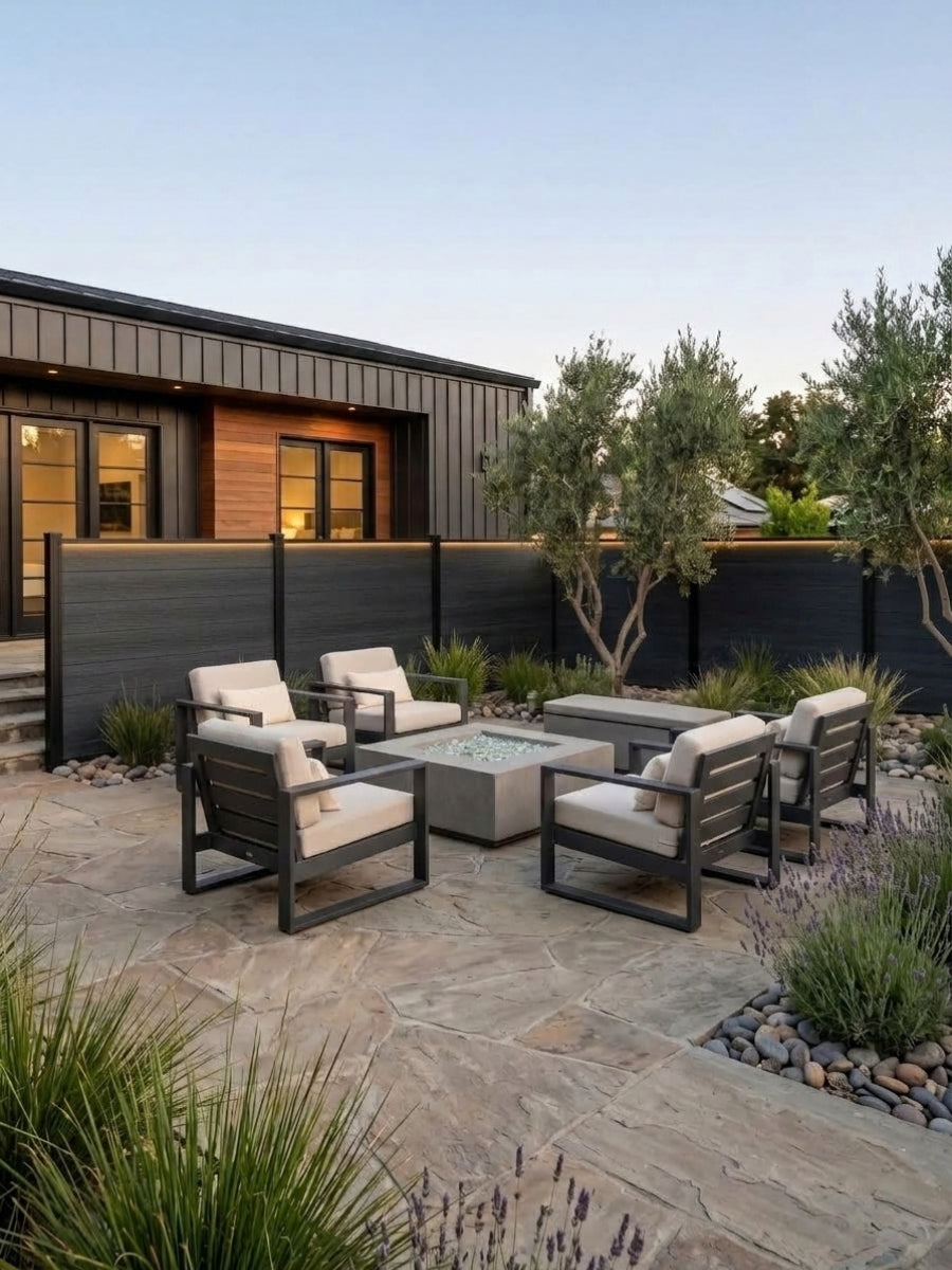 Black composite privacy fence installed behind an outdoor dining area and landscaped garden