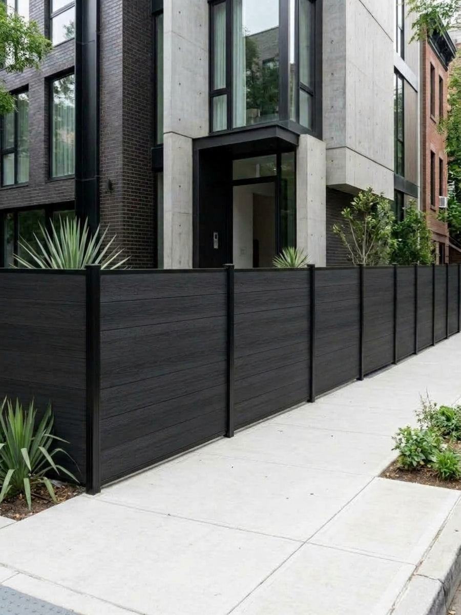 Black composite privacy fence panels lining a landscaped sidewalk outside a modern residence