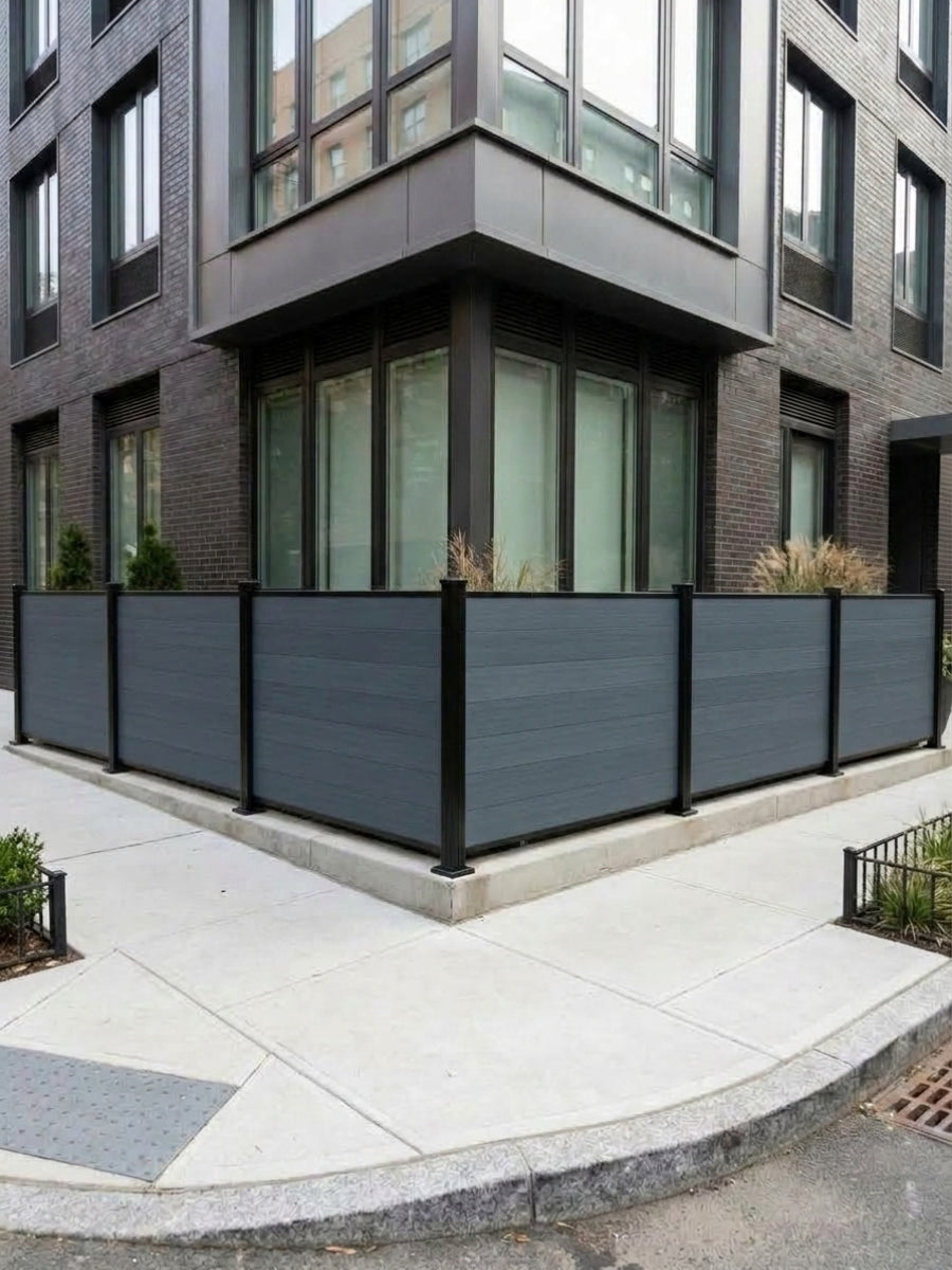 Light gray composite privacy fence wrapping around the corner of a modern urban building