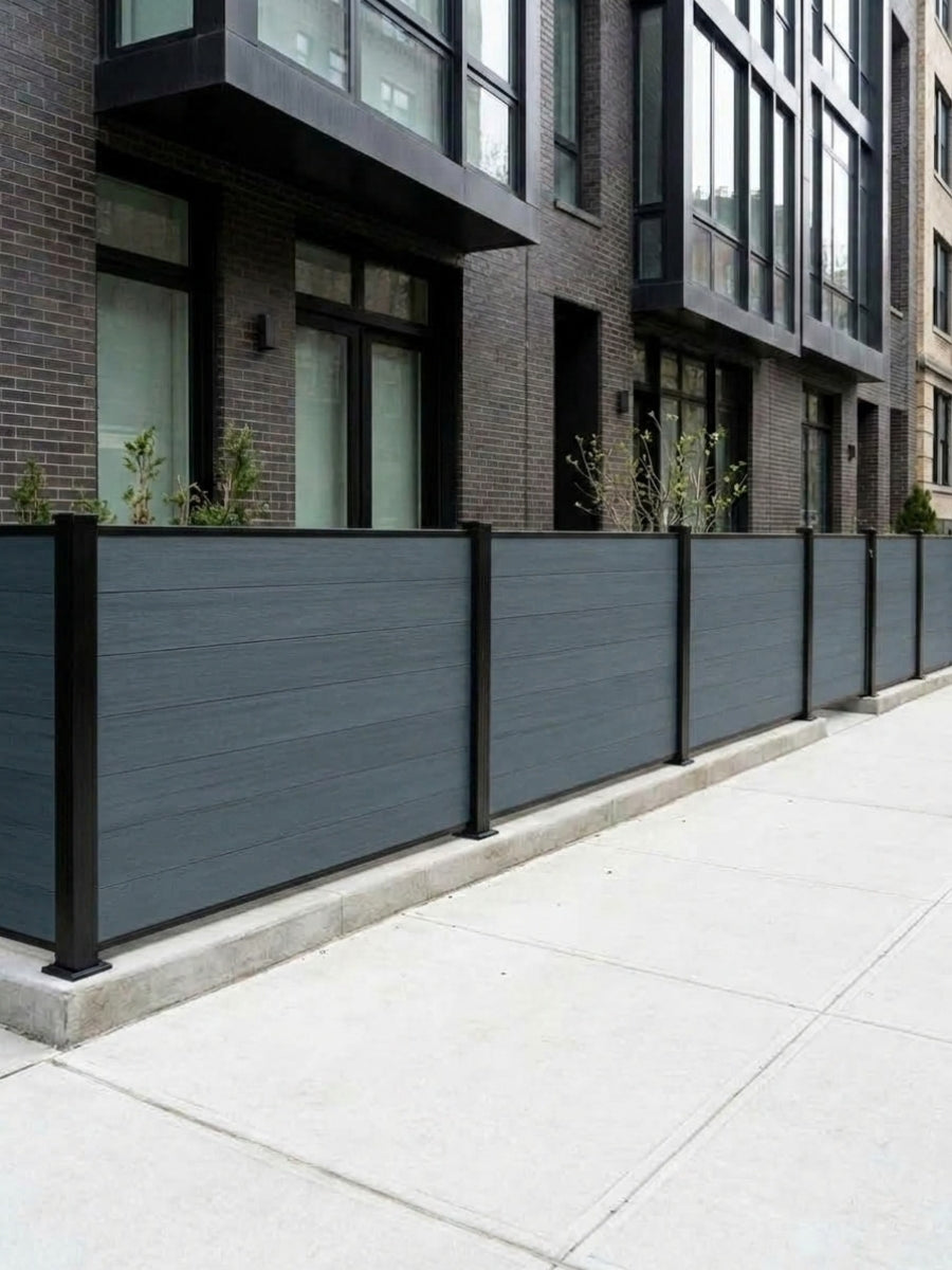 Light gray composite privacy fence panels with black posts installed beside a city sidewalk