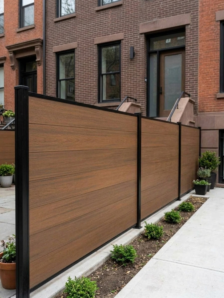 Walnut composite privacy fence panels with black posts installed along a sloped townhouse sidewalk